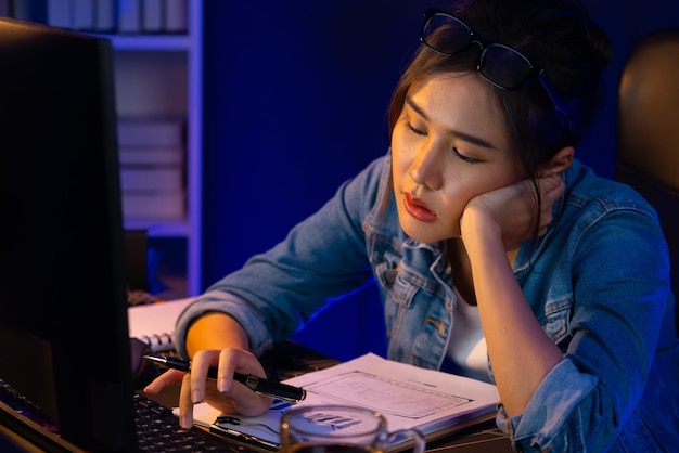 Jeune créatif asiatique épuisé, endormi, regardant Stratagem sur PC.