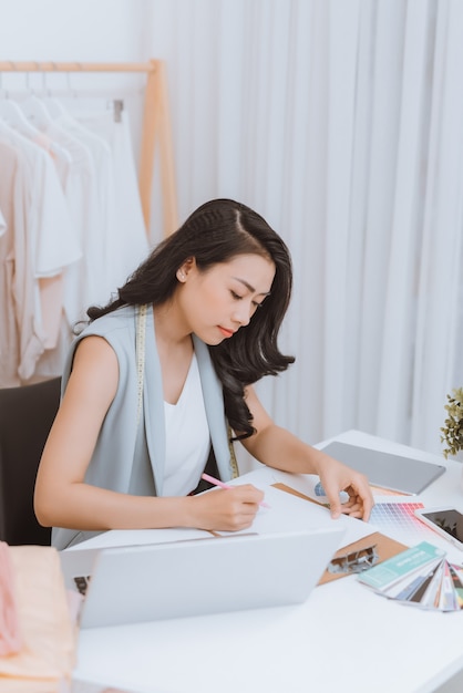 Une jeune créatrice de mode asiatique travaillant dans son atelier