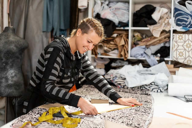 Une jeune créatrice de vêtements. Mesures en centimètres sur le tissu pour la confection de vêtements. Confection de vêtements sur commande, concepteur de mode