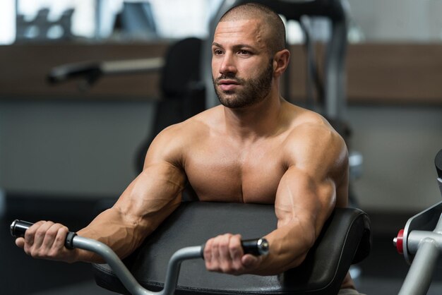 Jeune culturiste exerçant des biceps sur la machine