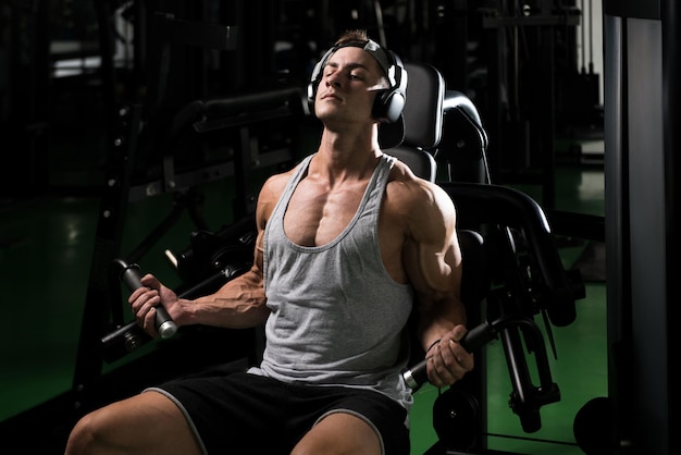 Jeune culturiste faisant des exercices de poids lourds pour les biceps sur la machine