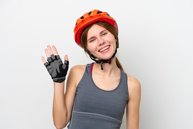 Jeune cycliste anglaise femme isolée sur fond blanc saluant avec la main avec une expression heureuse