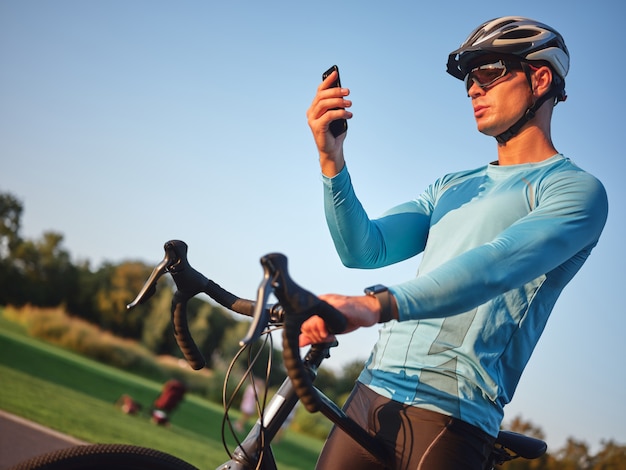 Jeune cycliste professionnel de la technologie portant un casque de protection de vêtements de sport et des lunettes tenant