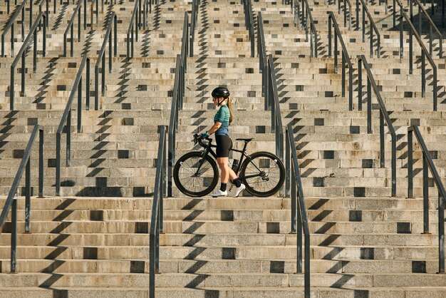 Jeune cycliste professionnelle en vêtement de cyclisme et équipement de protection debout sur les marches avec