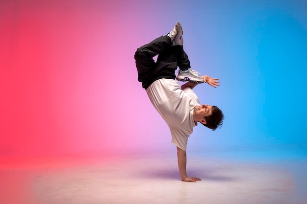 Un jeune danseur danse dans l'éclairage au néon. Un acrobate fait des tours et danse.