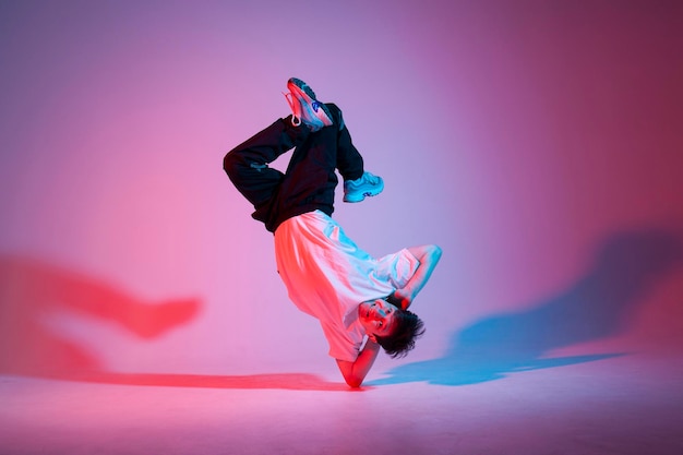 un jeune danseur danse dans un éclairage au néon, un acrobate masculin fait des tours et danse