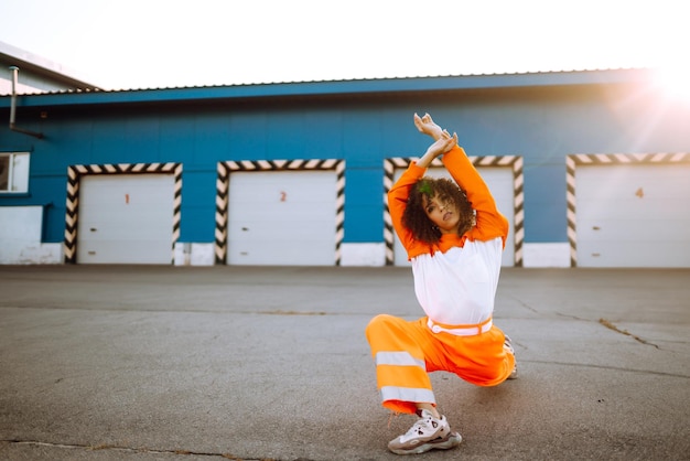 Une jeune danseuse afro-américaine dansant dans la rue au coucher du soleil Une femme élégante aux cheveux bouclés