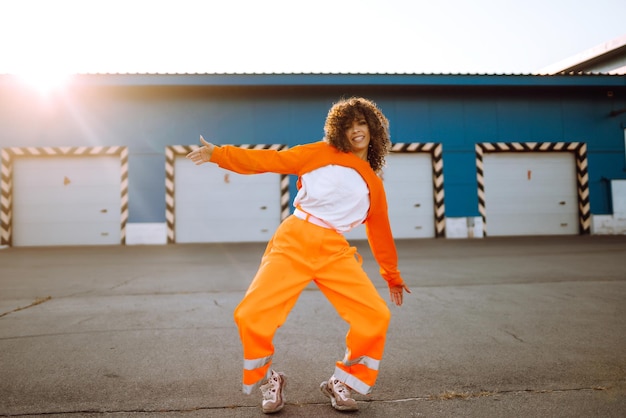 Une jeune danseuse afro-américaine dansant dans la rue au coucher du soleil Une femme élégante aux cheveux bouclés