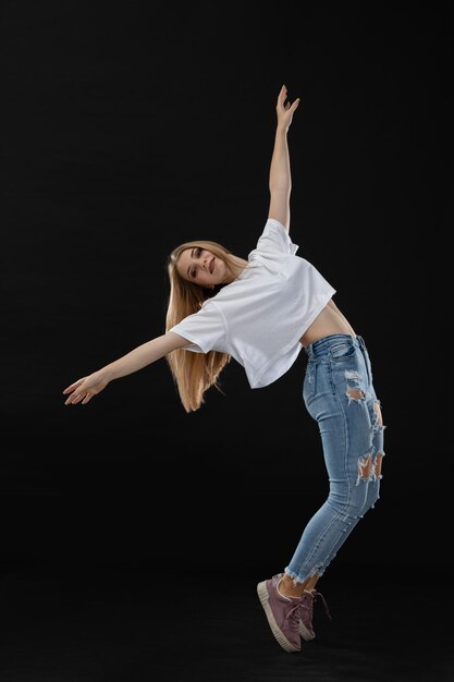 Une jeune danseuse aux longs cheveux blonds se tient sur la place.