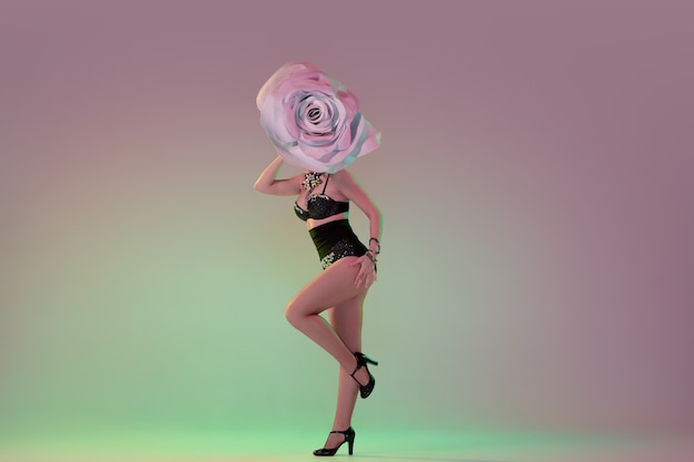 Jeune danseuse avec d'énormes chapeaux floraux en néon sur mur dégradé