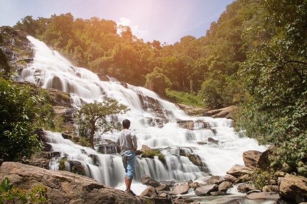 Jeune debout sur la pierre et en regardant la cascade