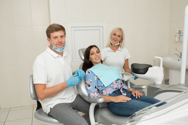 Un jeune dentiste et une patiente heureuse. Scène de vie de bureau de dentiste. Pratique du docteur. Soins de santé des patients