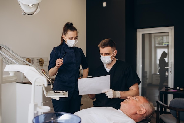 Jeune dentiste et son assistant traitant un homme âgé