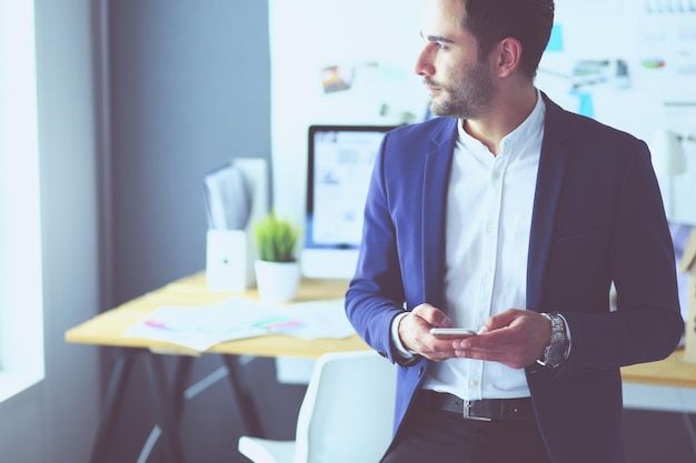 Jeune designer écrivant des sms dans son bureau