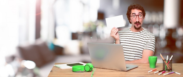 Jeune designer graphique fou sur un bureau avec un ordinateur portable