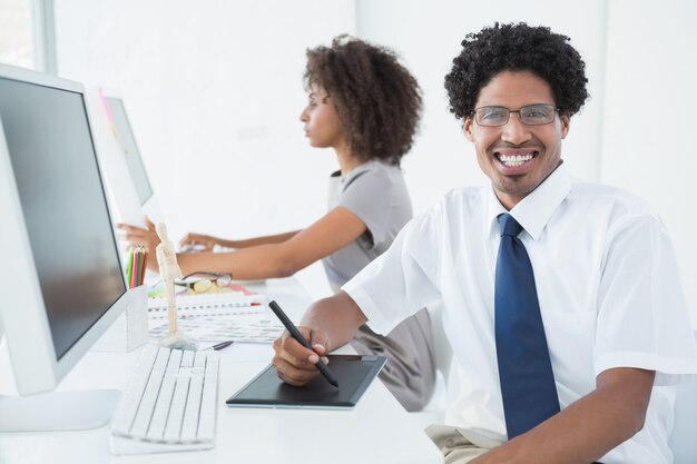 Jeune designer souriant à la caméra à son bureau