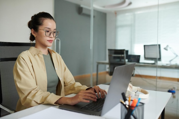 Jeune développeuse de logiciels travaillant sur un ordinateur portable à son bureau.