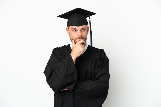 Jeune diplômé brésilien d'université isolé sur fond blanc ayant des doutes et pensant