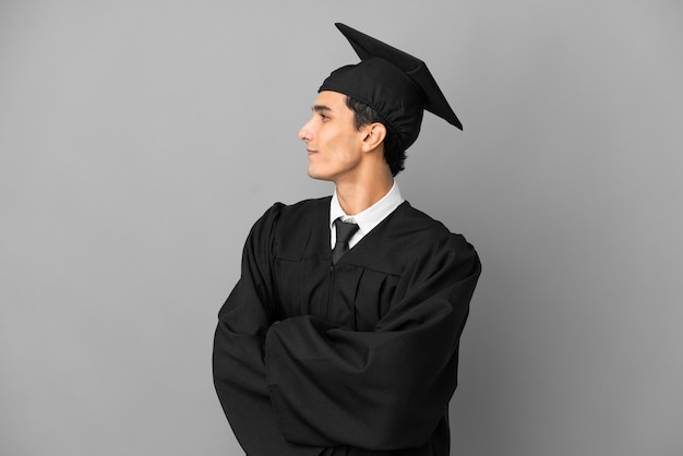 Jeune diplômé universitaire argentin isolé sur fond gris en position latérale