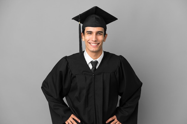 Jeune diplômé universitaire argentin isolé sur fond gris en riant