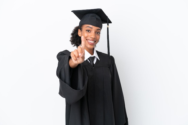 Jeune diplômé universitaire femme afro-américaine isolée sur fond blanc montrant et levant un doigt