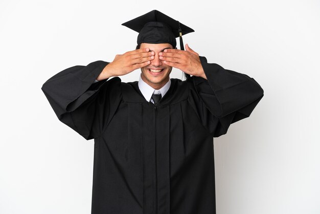 Jeune diplômé universitaire sur fond blanc isolé couvrant les yeux par les mains