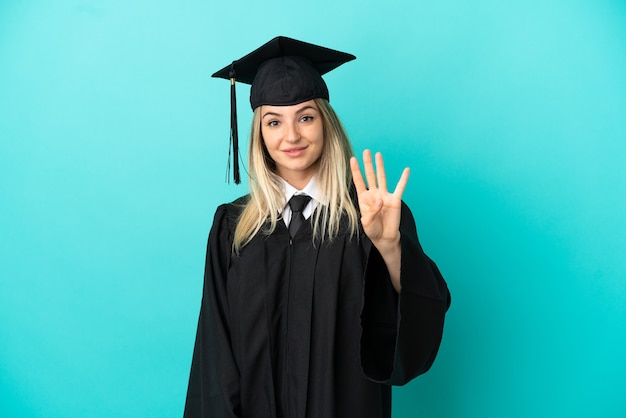 Jeune diplômé universitaire sur fond bleu isolé heureux et comptant quatre avec les doigts