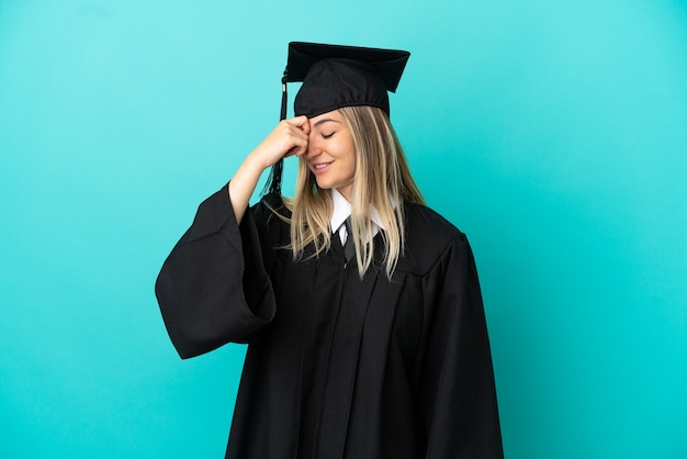 Jeune diplômé universitaire sur fond bleu isolé en riant