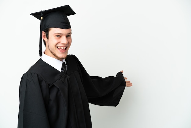 Jeune diplômé universitaire russe isolé sur fond blanc tendant les mains sur le côté pour inviter à venir