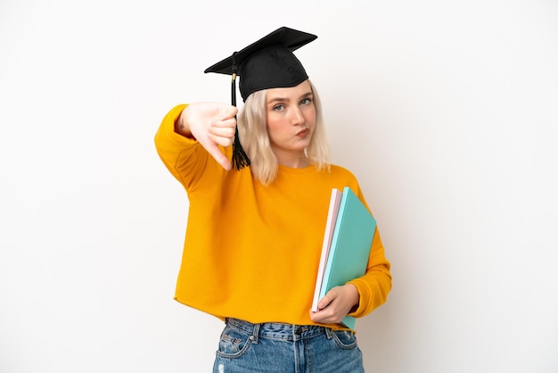 Jeune diplômé de l'université femme caucasienne isolé sur fond blanc montrant le pouce vers le bas avec une expression négative