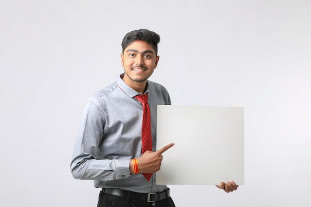 Jeune dirigeant d'entreprise indien montrant un panneau vierge sur fond blanc.