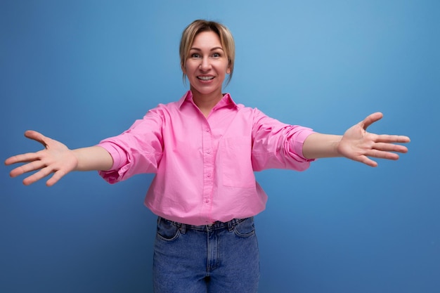 Photo une jeune dirigeante blonde européenne vêtue d'un blouse rose avec les bras ouverts.