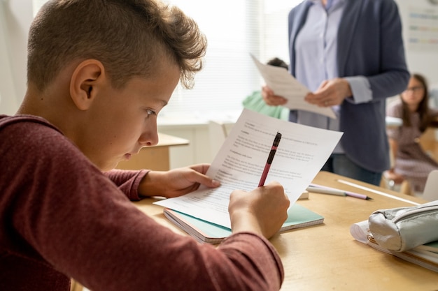 Jeune écolier effectuant un test par bureau