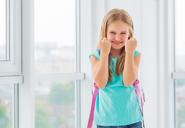 Jeune écolière heureuse de l'école, les poings serrés