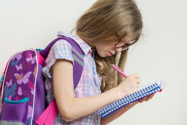 Jeune écolière à lunettes et avec sac à dos écrit