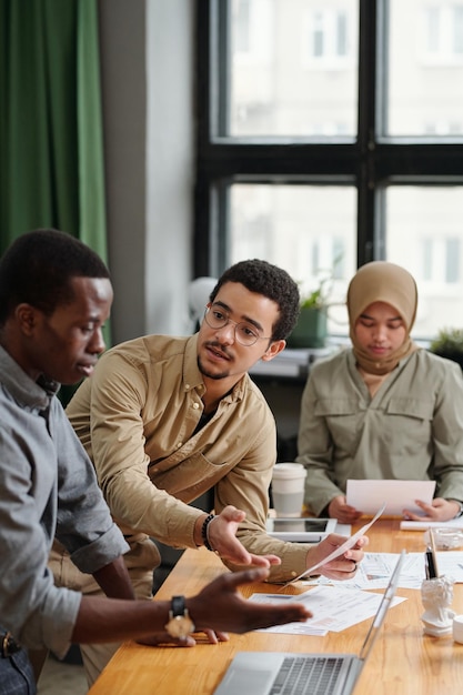 Jeune économiste masculin confiant avec un document regardant un collègue