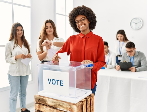 Photo jeune électrice souriante heureuse de voter au scrutin debout au centre électoral.