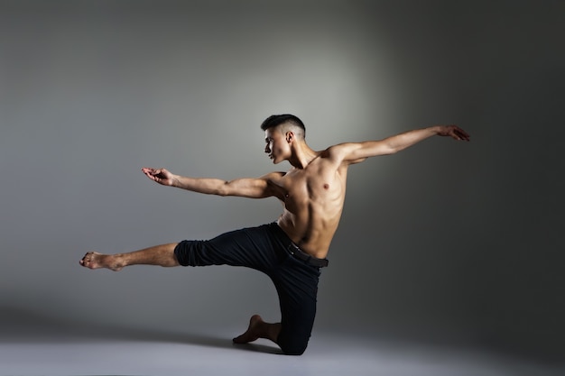 Jeune et élégant danseur de ballet moderne sur fond gris