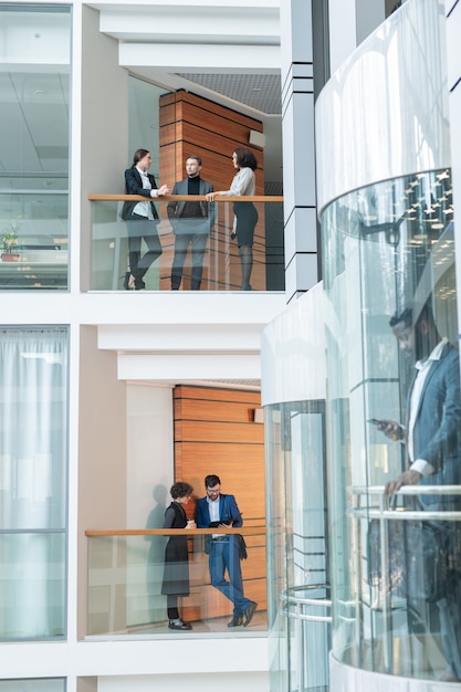 Jeune employé de bureau debout sur les balcons et discuter du travail dans le quartier financier moderne