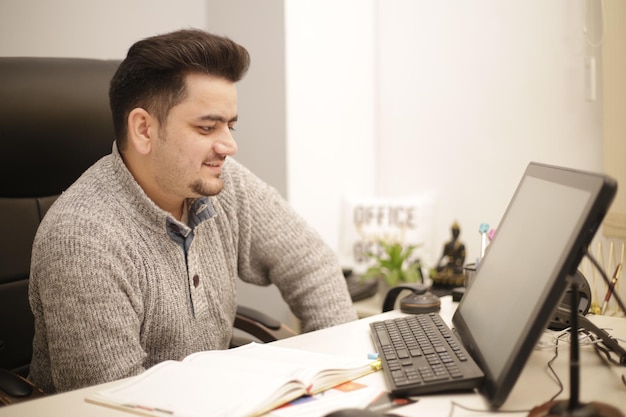 Photo un jeune employé regardant dans l'ordinateur et souriant.