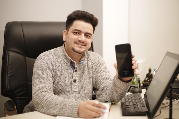 Photo un jeune employé tient un téléphone portable à la main et sourit.