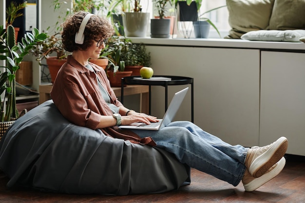 Jeune employée dans les écouteurs et les vêtements décontractés