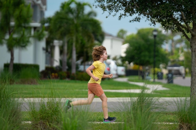 Jeune enfant courir et sourire dans le parc petit enfant actif qui court le long de la rue pendant les loisirs spor