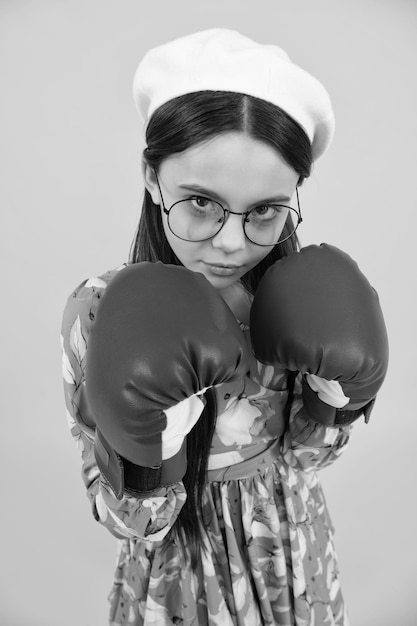 Jeune enfant fille à l'aide de gants de boxe avec visage drôle Portrait d'une adolescente gagnante surprise drôle dans des gants de boxe isolés sur jaune