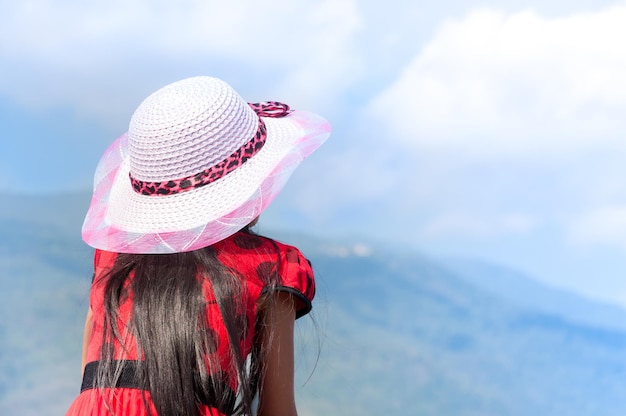 Jeune enfant fille chemise rouge avec porter un chapeau sur fond de nature dans le ciel bleu un symbole de succès en leadership et de liberté et de voyage