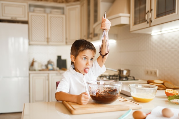 Jeune enfant mélanger le chocolat fondu dans un bol