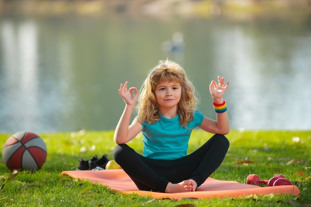 Jeune enfant pratiquant le yoga à l'extérieur lotus pose yoga harmonie et concept de méditation mode de vie sain