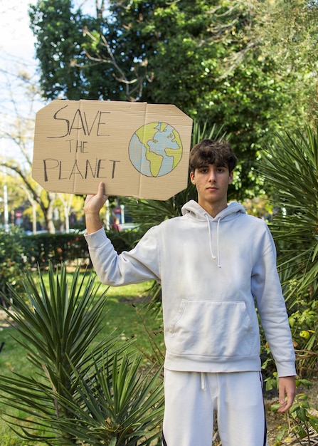 Photo un jeune enfant tenant dans ses mains des affiches vertes sur la non-guerre dans le monde la jeunesse manifeste pour une écologie sûre