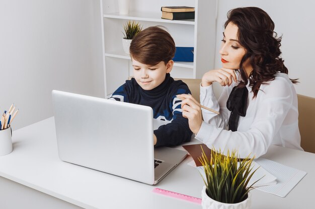 Jeune enseignant avec enfant à faire ses devoirs sur un ordinateur. Aide du tuteur.