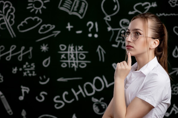 Jeune enseignant est debout près de tableau noir en classe